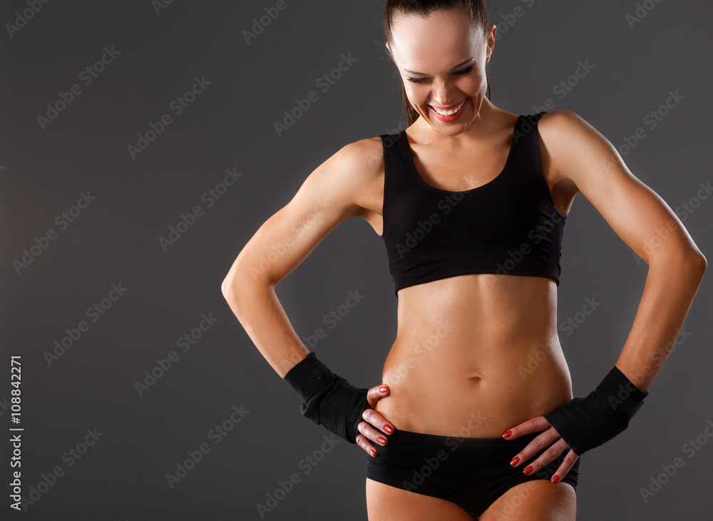Obraz premium Muscular young woman standing on gray background