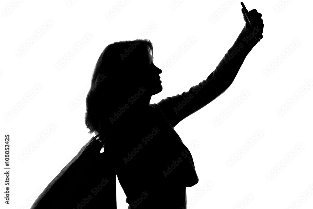 silhouette of a woman with shopping bags doing selfie