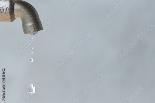 leaking silver faucet with water drop, close up, copy space
