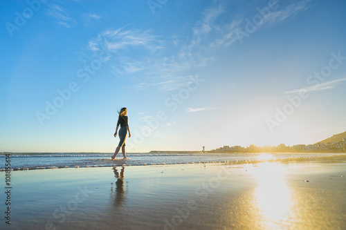 Woman in dress walk on the beach at sunset time.