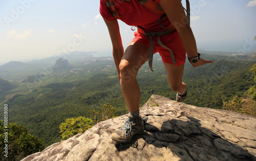 young asian woman hiker climbing rock on mountain peak cliff