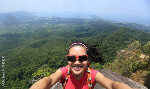 young woman hiker use smartphone taking self photo on seaside mountain top