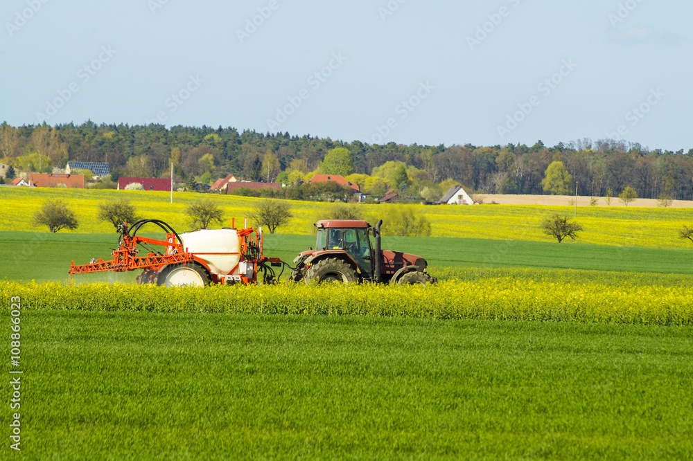 Fototapeta premium traktor rolniczy podczas oprysków chemicznych na wiosennym polu