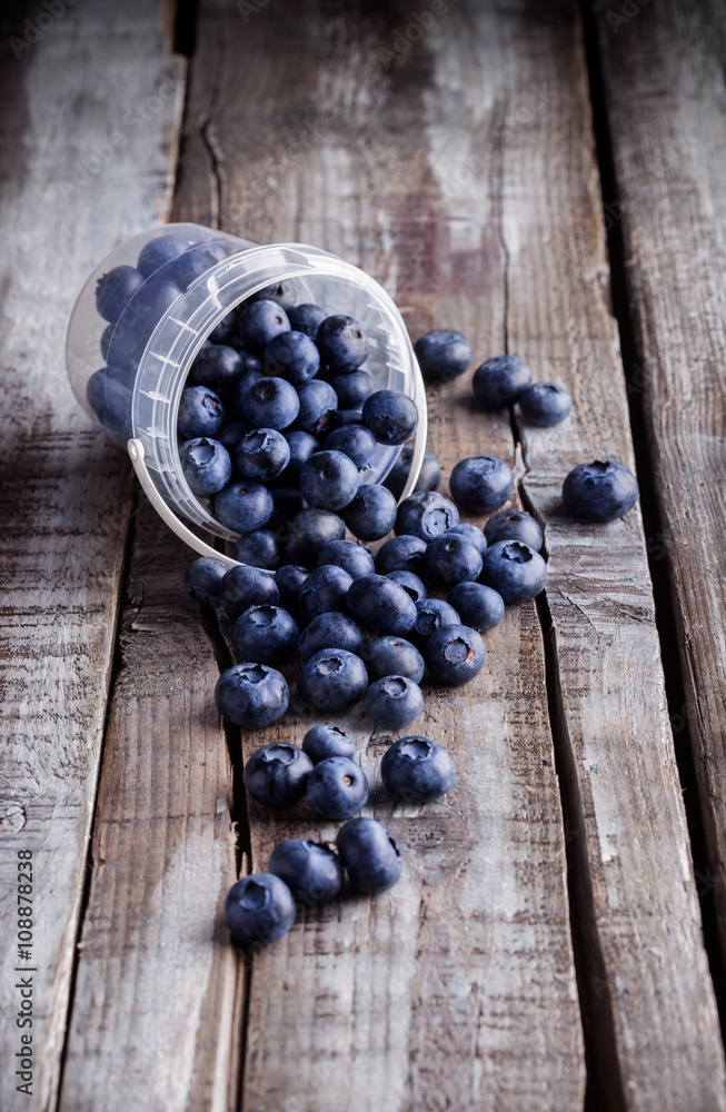 Blueberries in a plastic can on old rustic wooden table Blueberries in a plastic can on old rustic wooden table