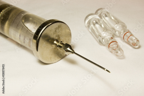 Iron vintage glass syringe with needles on a white background.