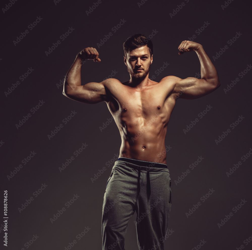 Athletic handsome man showing biceps muscles, studio shot