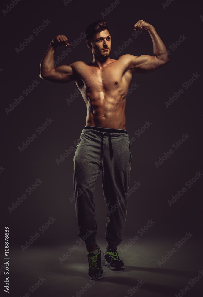 Athletic handsome man showing biceps muscles, studio shot Athletic handsome man showing biceps muscles, studio shot