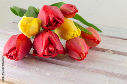 Red and yellow tulips on wooden table