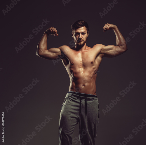 Athletic handsome man showing biceps muscles, studio shot © Alex Tihonov