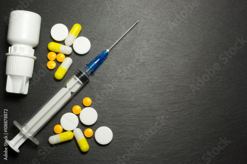 Medical syringe and pills on dark background