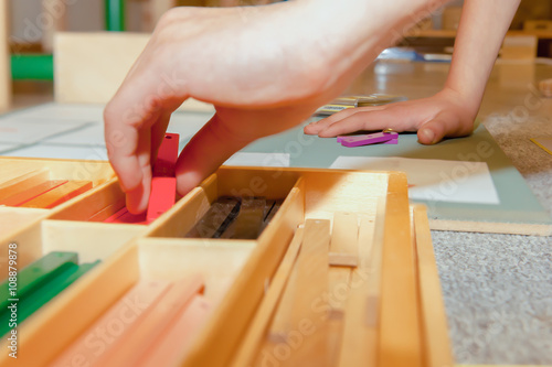 Montessori Child works with Geometric Stick Material on Cork Board photo