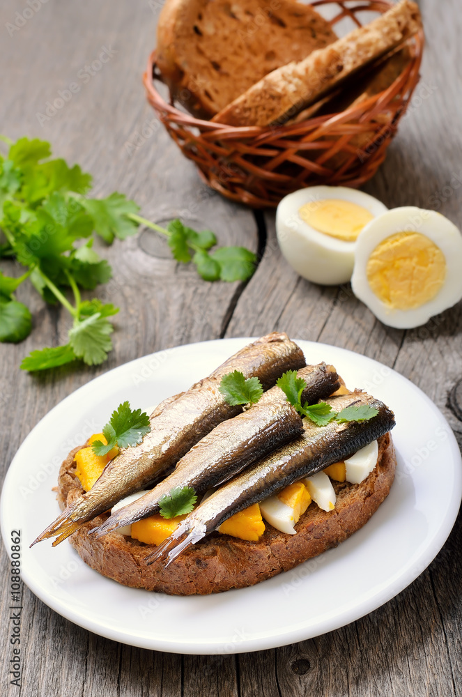 Appetizer bread with sprats  and egg on white plate