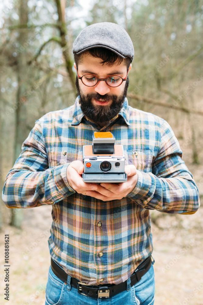 Fototapeta premium Young man bearded with film photocamera in the forest