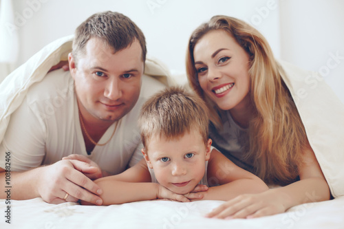 Happy family relaxing in bed