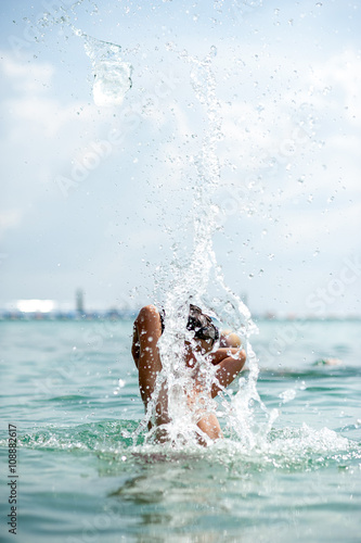 Young boy playing in the ocean splashing water
