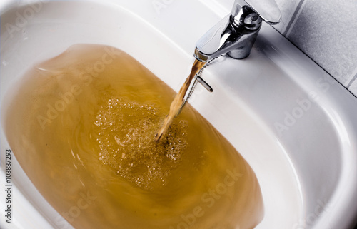 Dirty brown water running into a sink