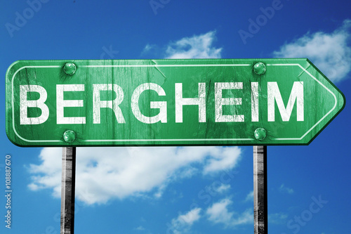 Bergheim road sign, vintage green with clouds background