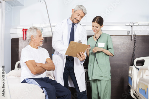 Doctor And Nurse Communicating Over Report By Senior Patient
