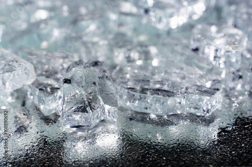 pile of different ice cubes on reflection table with water drops