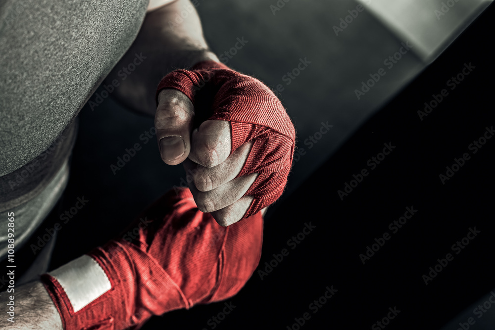 Closeup male hand of boxer with red boxing bandages. Fists of fighter  before the fight or training in sport gym. Photos