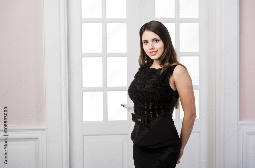 Beautiful woman standing in a black dress over studio loft home interior doors behind Beautiful woman standing in a black dress over studio loft home interior doors behind