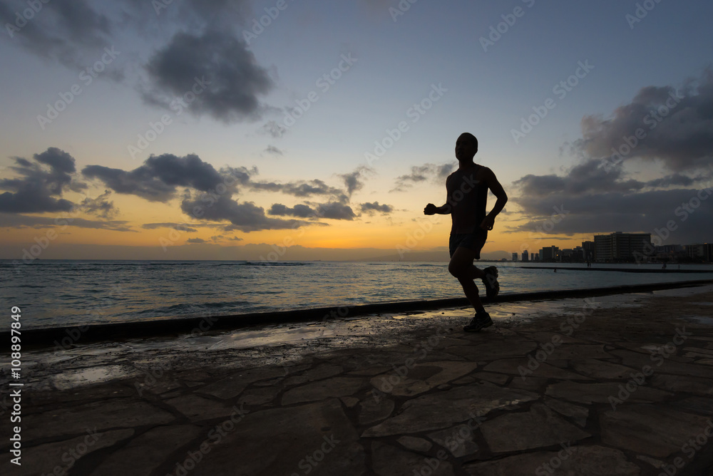 Fototapeta premium Silhoutte of runner jogging along Waikiki beach at sunset golden hour
