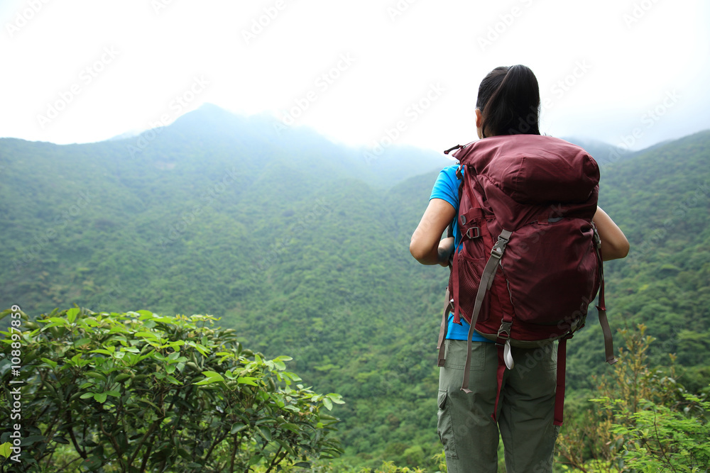 young woman backpacker on spring forest mountain peak
