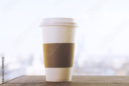 Coffee cup on blurry city