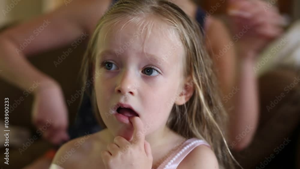 Mother brushes daughter's hair watching cartoon Mother brushes daughter's hair watching cartoon