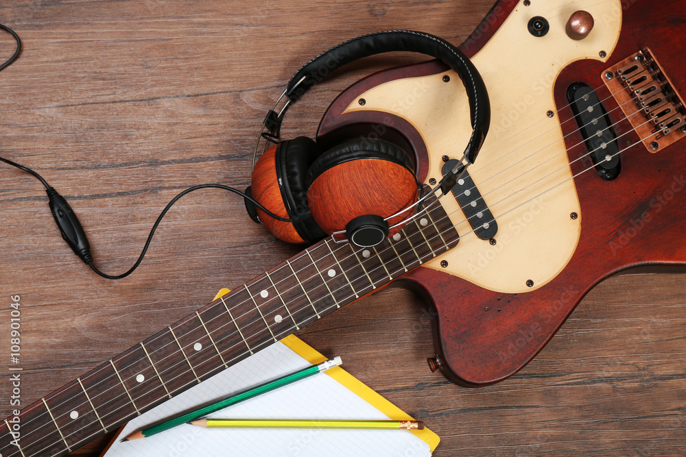 Naklejka premium Electric guitar and headphones on wooden background