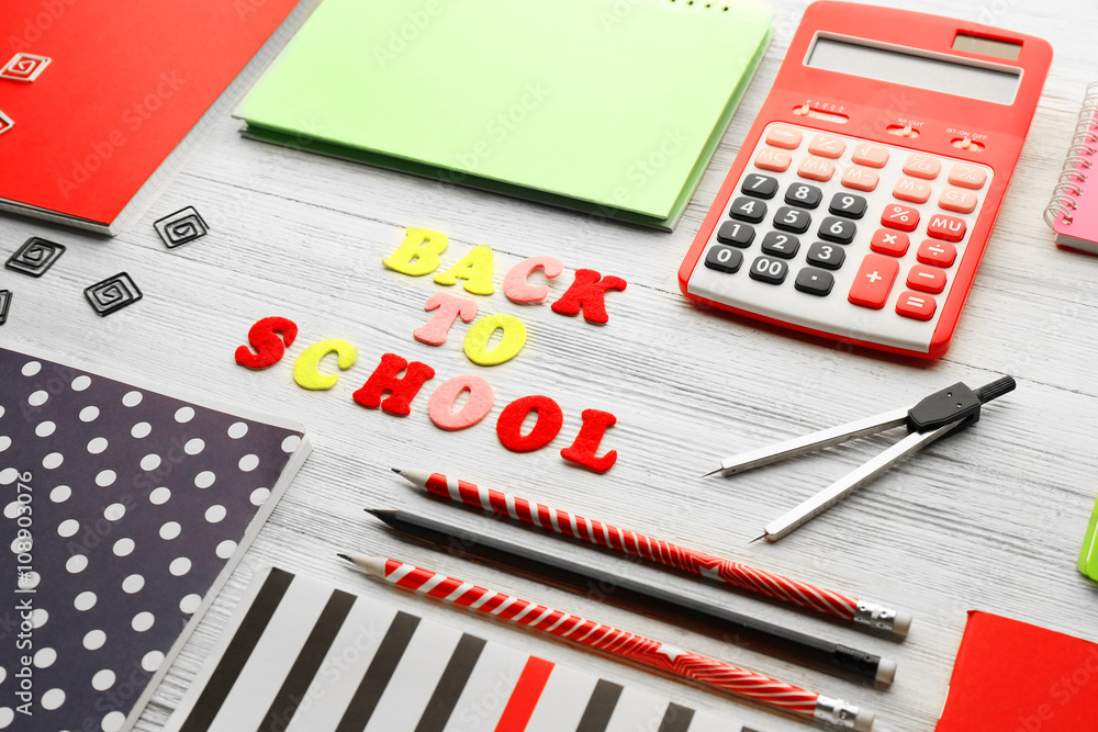 School set with back to school inscription, notebooks and calculator on light wooden background