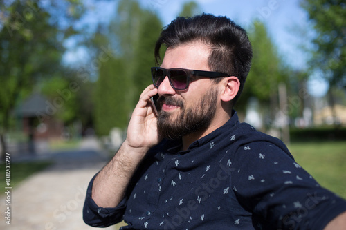 Happy man using a smart phone outdoor with a green background