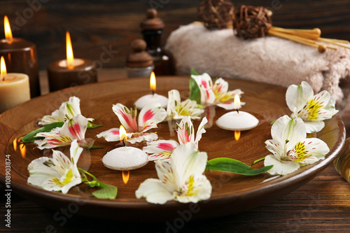 Spa wooden bowl with water and flowers closeup