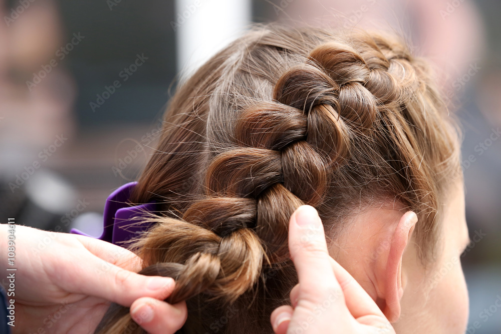 Fototapeta premium Professional hairdresser braiding clients hair