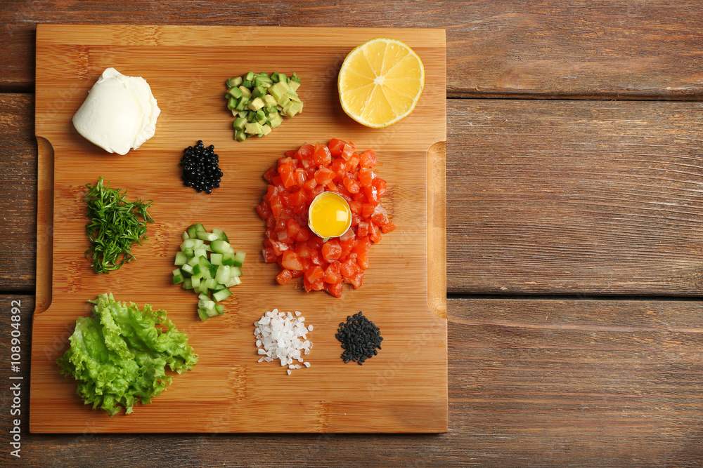 Tasty ingredients of salmon tartare on cutting board, flat lay Tasty ingredients of salmon tartare on cutting board, flat lay