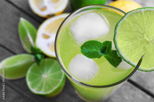 Glasses of lemon soda with ice and fresh mint on rustic wooden background