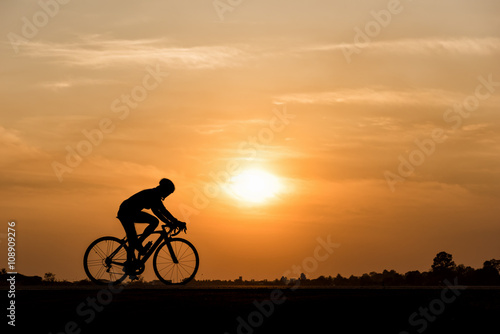 Fotografie Silhouette of cycling on sunset background