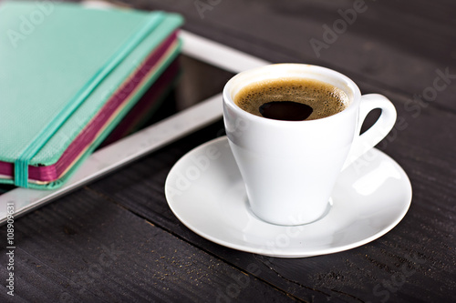 Smart phone with notebook and cup of strong coffee on wooden background. Cellphone with writing set with espresso