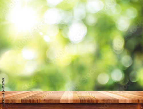 Empty brown wood table top with sun and blur green tree bokeh ba
