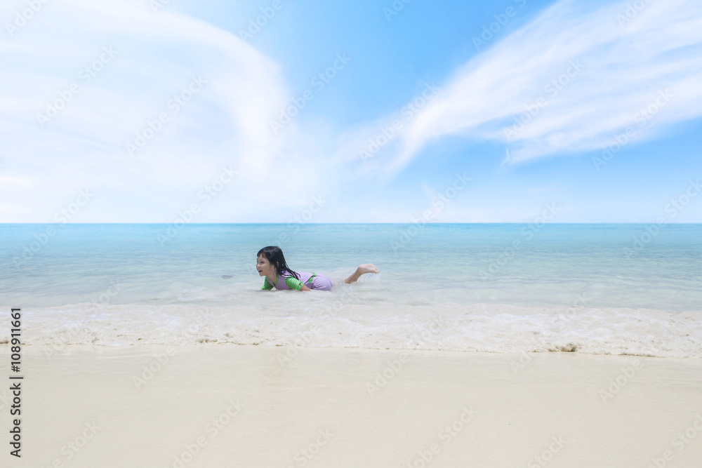Happy little girl playing on the tropical beach