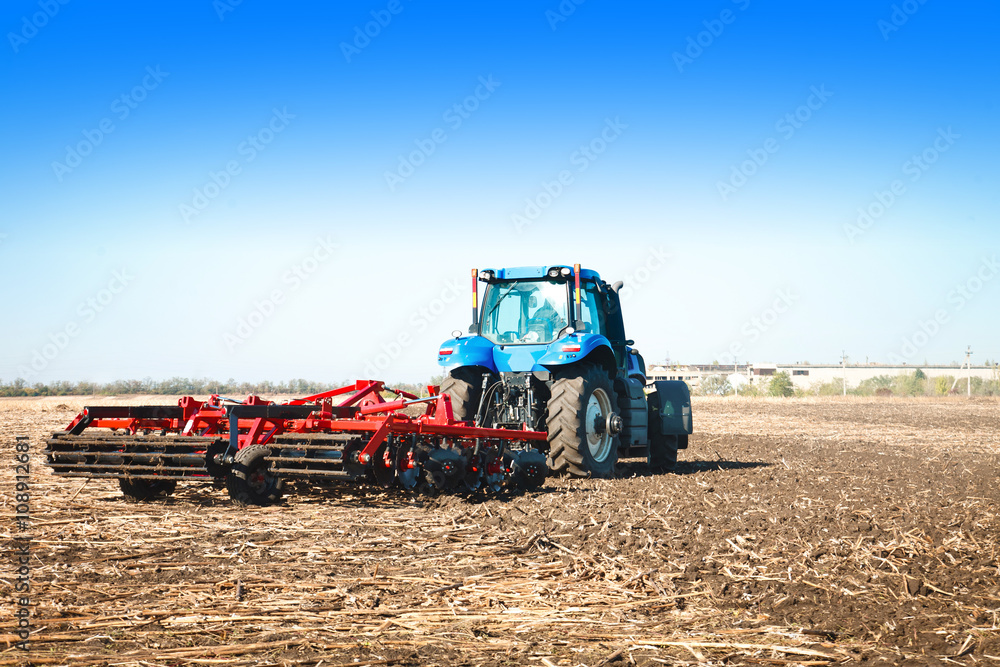 Fototapeta Blue tractor working in an open field