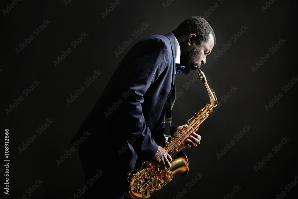 Obraz premium African American jazz musician playing the saxophone on grey background