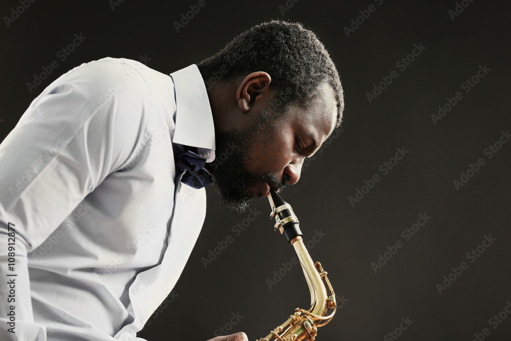 Naklejka premium African American jazz musician playing the saxophone on grey background