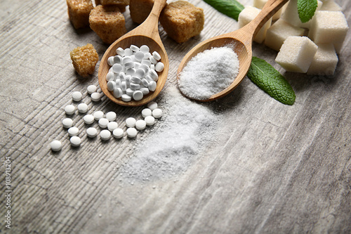 Pile of brown sugar cubes and stevia on grey wooden background