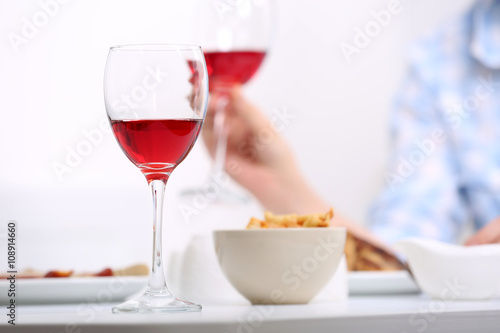 Dinner with glasses of wine on light blurred background