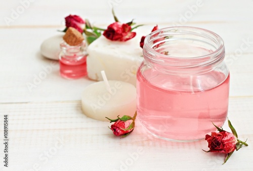 Rose water in jar, dried roses, candle, relaxing aromatherapy. Soft focus, soft light.