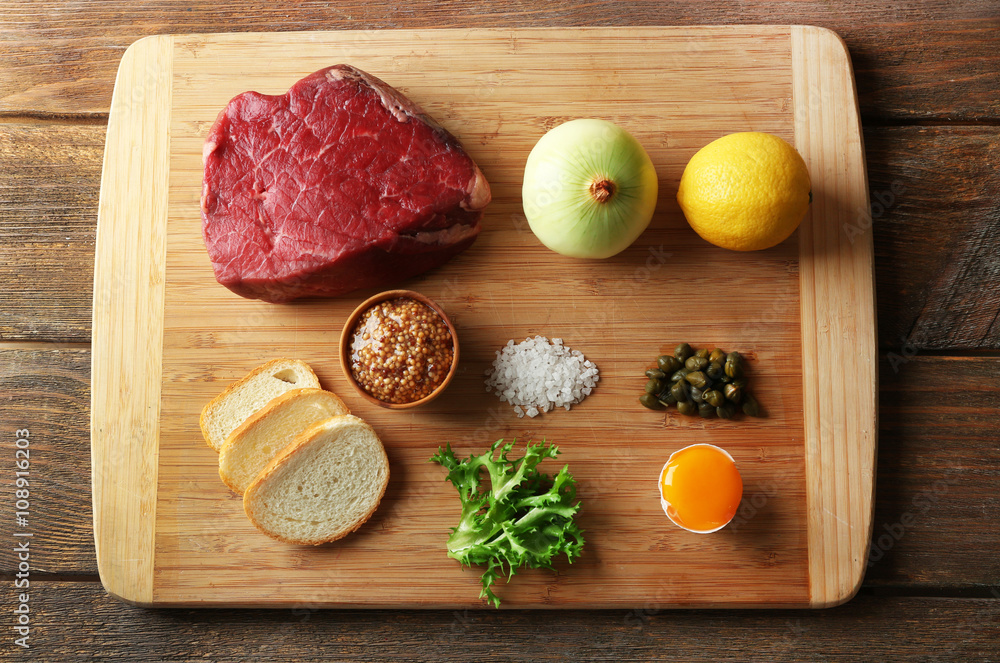 Beef tartare ingredients on wooden cutting board Beef tartare ingredients on wooden cutting board