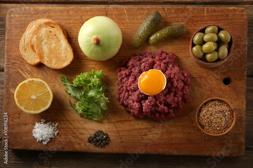 Beef tartare ingredients on wooden cutting board