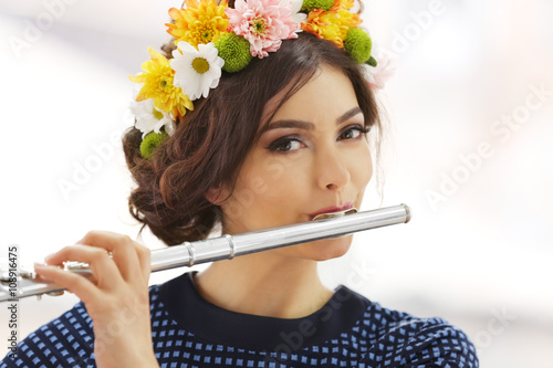 Beautiful young woman with flute on window background