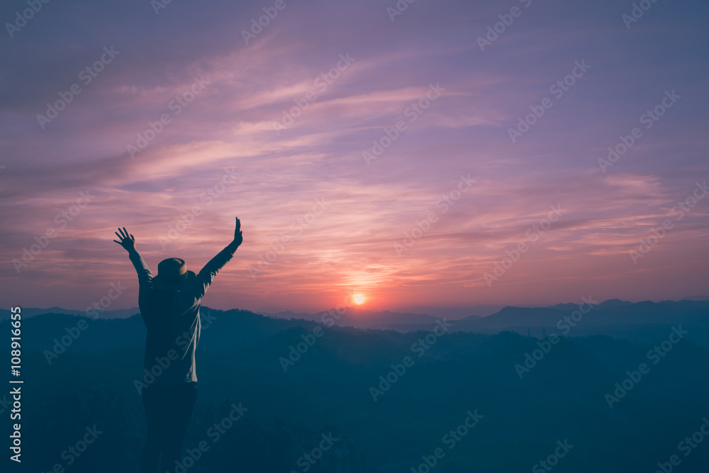 Young woman cheering open arms at mountain and sunset. Vintage filter.